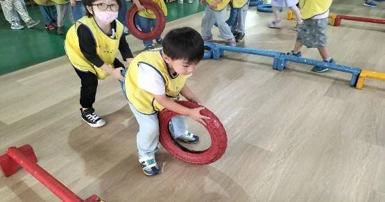 幼兒在草地上進行滾輪胎與大肌肉體能遊戲